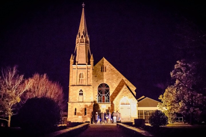 a church with a clock tower in front of a house